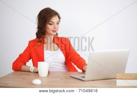 Attractive woman sitting at desk in office, working with laptop