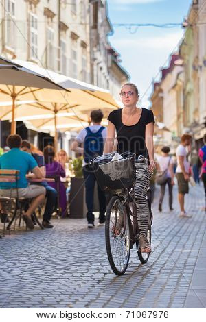 Woman riding bicycle in city center.