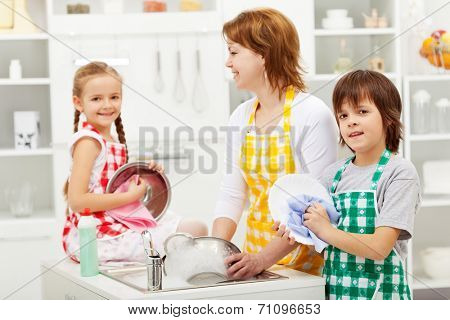 Kids and their mother washing dishes in the kitchen