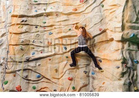 Woman climbing on man-made cliff in the sport centre