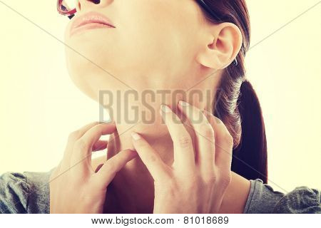 Young caucasian woman is scratching her neck.