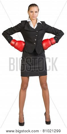 Businesswoman wearing boxing gloves standing akimbo