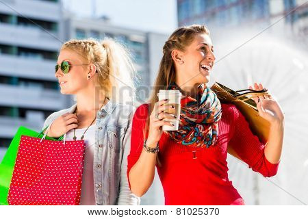 Women shopping in city with bags having coffee and bags in hands