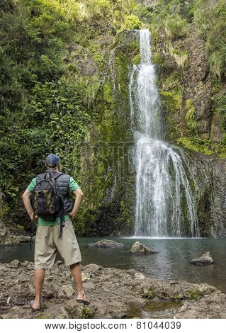 Man hiking to a beautiful tropical waterfall 