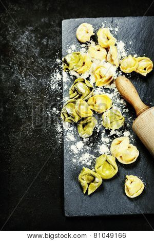 Homemade raw Italian tortellini on dark vintage background