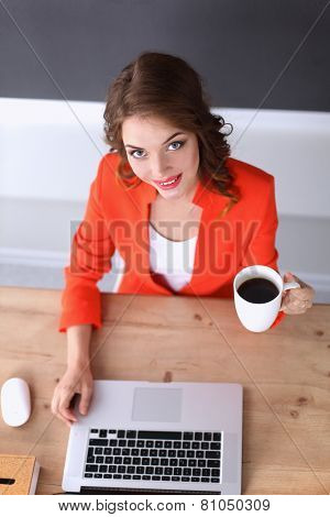 Attractive woman sitting at desk in office, working with laptop