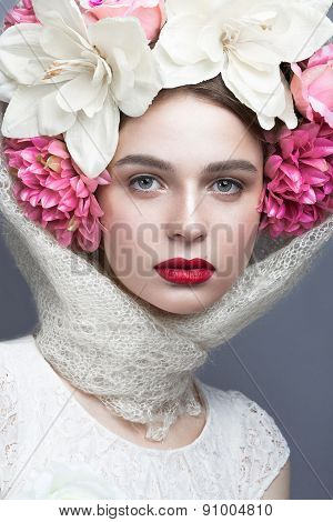 Beautiful girl in a headscarf in the Russian style, with flowers on the head and red lips.
