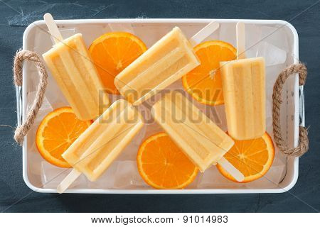 Homemade orange popsicles in a rustic ice tray