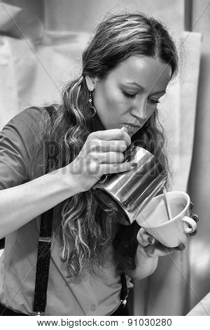 Female bartender in the workplace. Girl makes coffee using coffee machine.