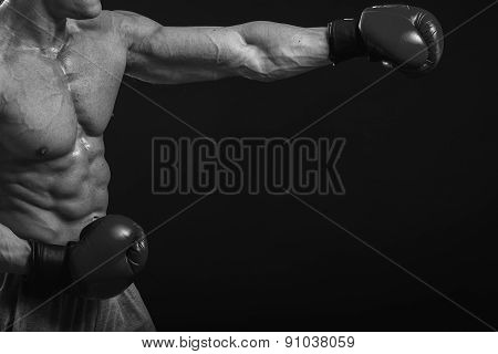 The man in boxing gloves. Young Boxer fighter over black background