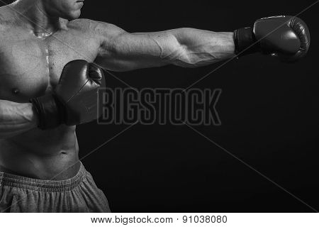 The man in boxing gloves. Young Boxer fighter over black background