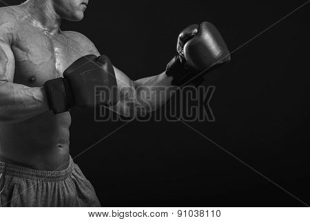 The man in boxing gloves. Young Boxer fighter over black background