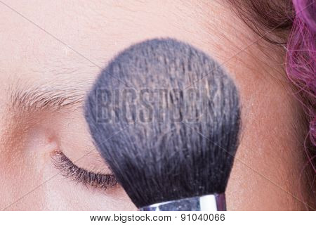Application of powder on the model's face. Makeup artist in a beauty salon doing make-up special bru