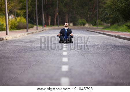 Businessman meditating sit in the middle of the street