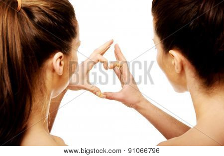 Two beautiful women making heart with fingers.