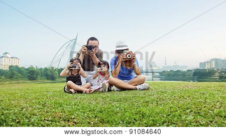 Happy Mother, Father And Daughter Take Picture In The Park