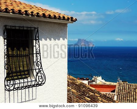 Spanish grated window of old house and sea in background