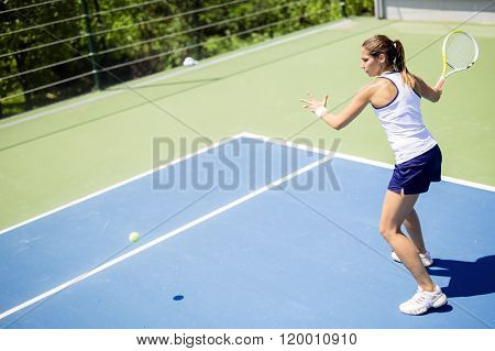 Beautiful female tennis player in action hitting a forehand