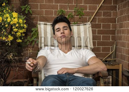 Handsome young man smoking a cigarette outside