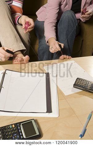 Two female students painting their toenails