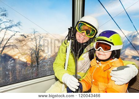 Mom and son skiers sit in cable car ski lift