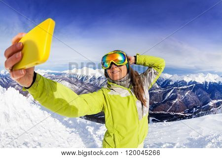 Woman take selfie over mountain and ski tracks