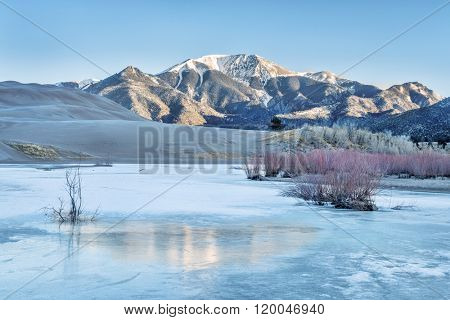 Sunrise over frozen Medano Creek with Sangre De Cristo Mountains in background, Great Sand Dunes National Park, Colorado