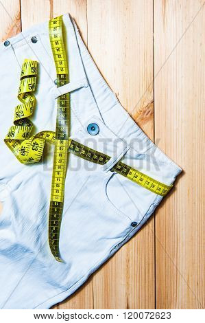 White jeans and measuring tape on wooden background
