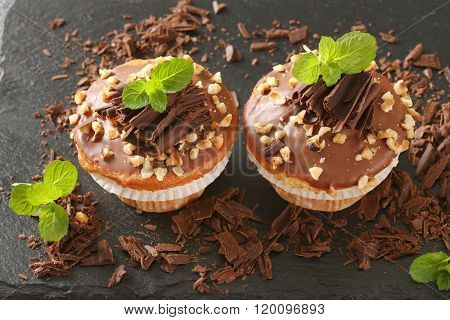 close up of chocolate muffins with chopped nuts on wooden cutting board