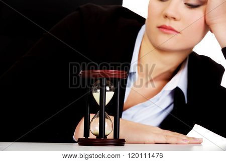 Young business woman sleeping on the desk with hourglass