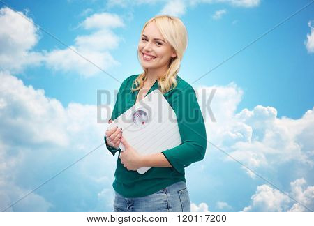 weight loss, diet, slimming, plus size and people concept - smiling young woman holding scales over blue sky and clouds background