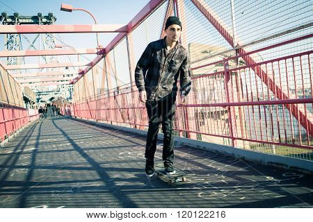 Young skateboarder speed through the pedestrian walkway on Williamsburg Bridge NYC. Photographed in Feb 2016.