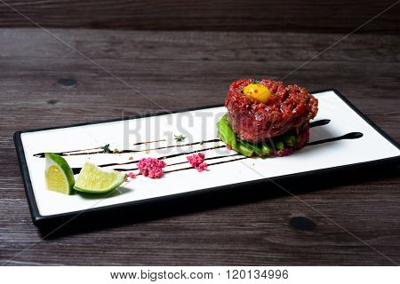 juicy Tartar of beef served with lime on white dish