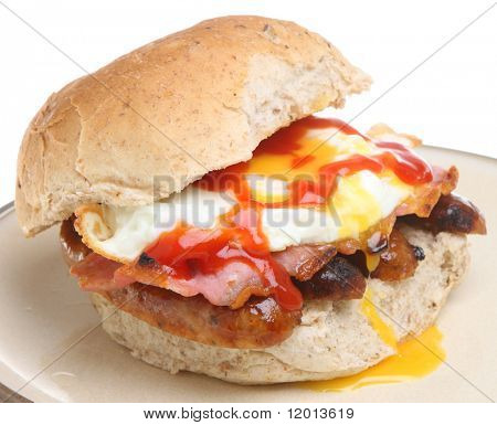Kornkammer brød roll med stegte æg, bacon, pølser og tomat ketchup.