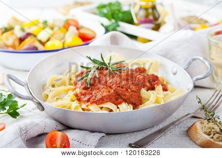 Tagliatelle pasta with tomato sauce and red pesto Top view