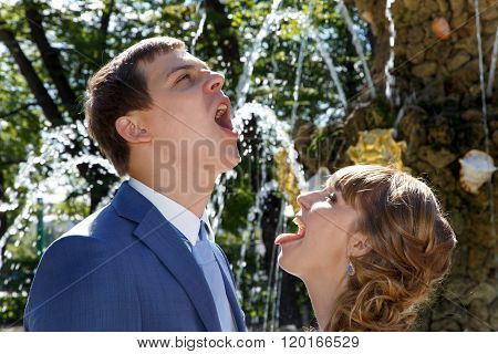 Young Wedding Couple Drinking Water From Fountain In Park