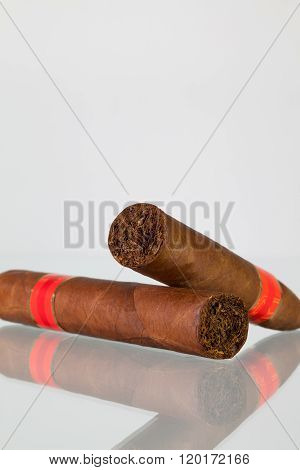 Different cigars on a glass table and white background