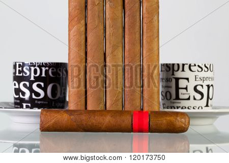 Different cigars and cups of coffee on a glass table and white background