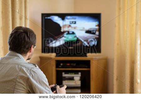 Man Playing Racing Video Game On Console In Home - Stock Photo