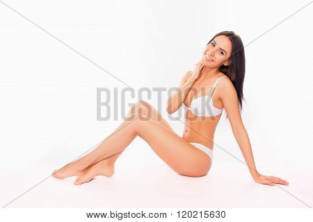 Smiling Slim Brunette Sitting In Lingerie On White Background