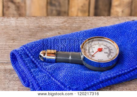 Tire Pressure Gauge And Microfiber Cloth On Wooden Table