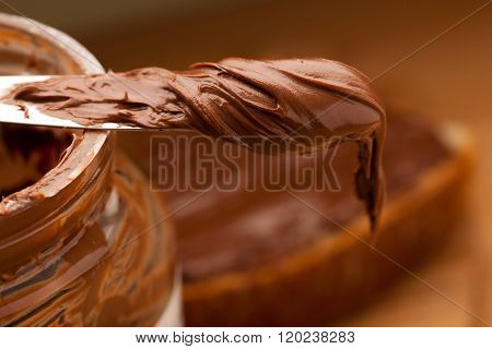 Knife Full Of Sweet Chocolate Nougat Spread On Glass Jar.