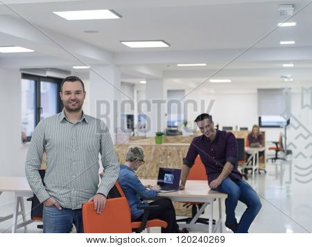 portrait of young businessman in casual clothes at modern  startup business office space,  team of people working together in background