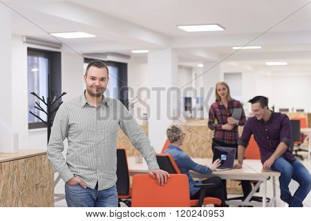 portrait of young businessman in casual clothes at modern  startup business office space,  team of people working together in background