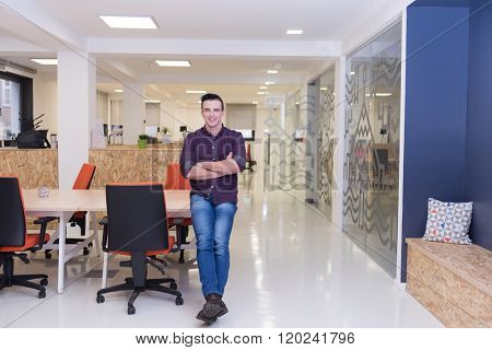 portrait of young business man in casual clothes sitting on table at  new startup office space and working on tablet computer