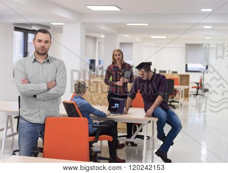 portrait of young businessman in casual clothes at modern  startup business office space,  team of people working together in background
