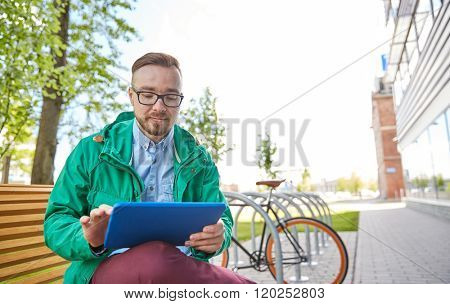 people, style, technology and lifestyle - happy young hipster man with tablet pc computer and fixie bike sitting on bench in city