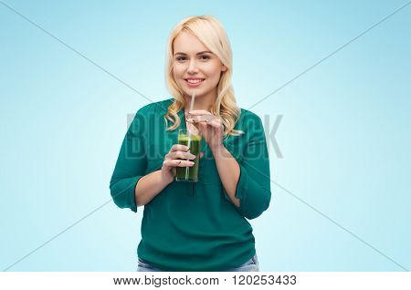 healthy eating, vegetarian food, diet, detox and people concept - smiling young woman drinking green vegetable juice or smoothie from glass over blue background