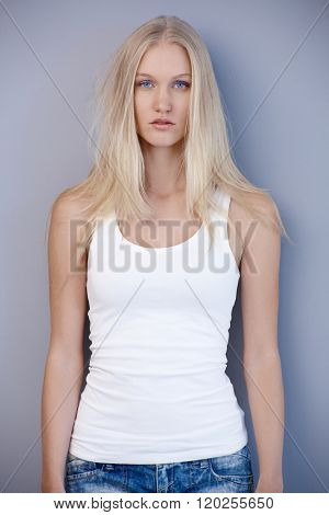 Beautiful scandinavian woman standing by wall, looking at camera serious.
