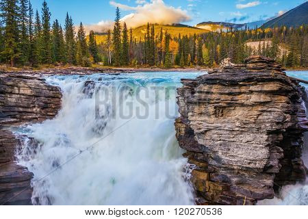 Canada, Jasper National Park. Powerful and scenic Athabasca Falls. Sunset sun illuminates the surrounding mountains